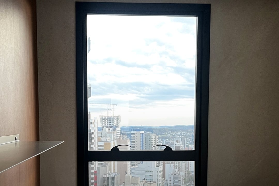 Consultório com janela ampla, bancada e mesa de trabalho.